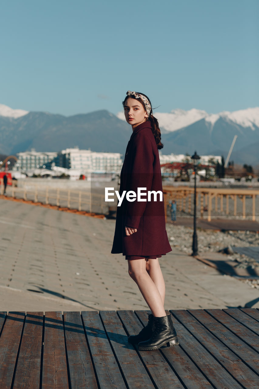 Portrait of young woman standing on mountain against sky