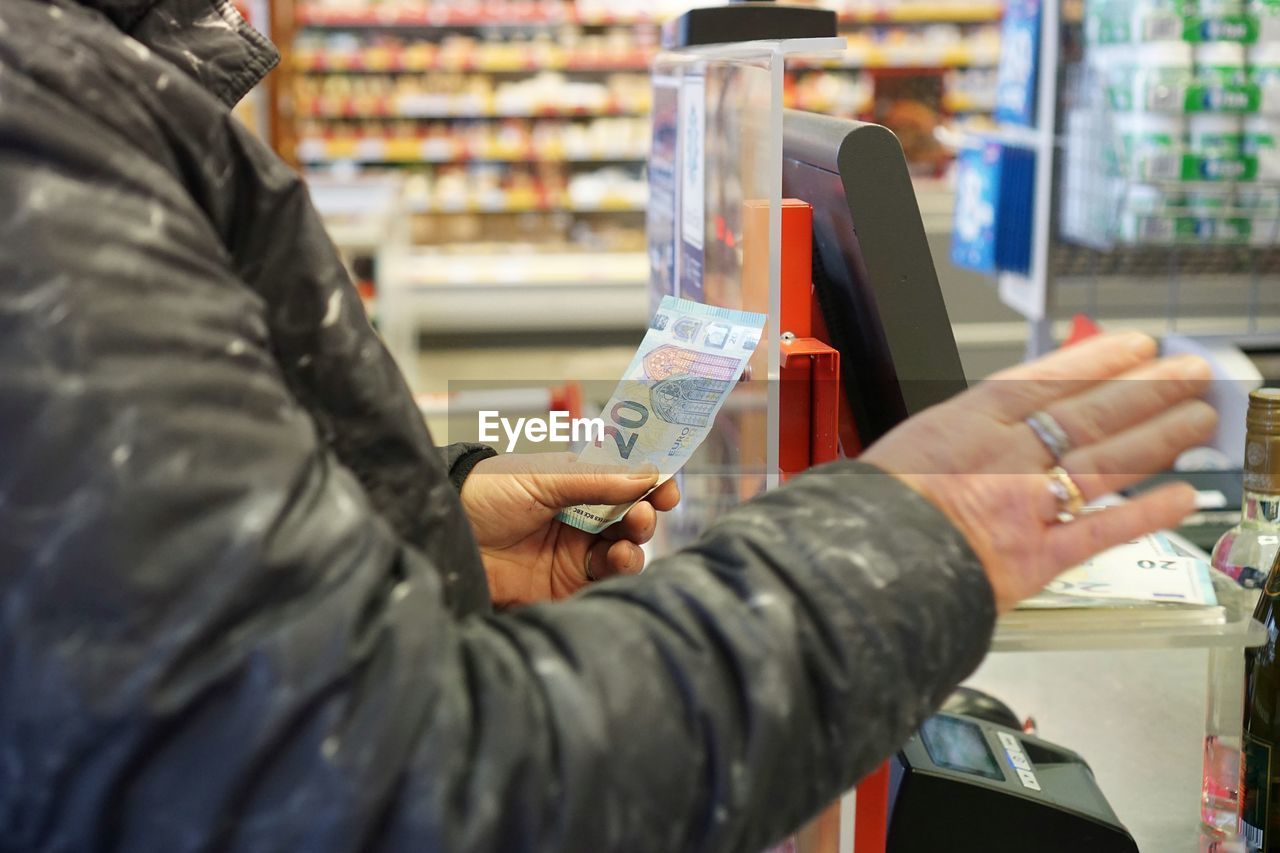 Midsection of man holding paper currency while standing in store