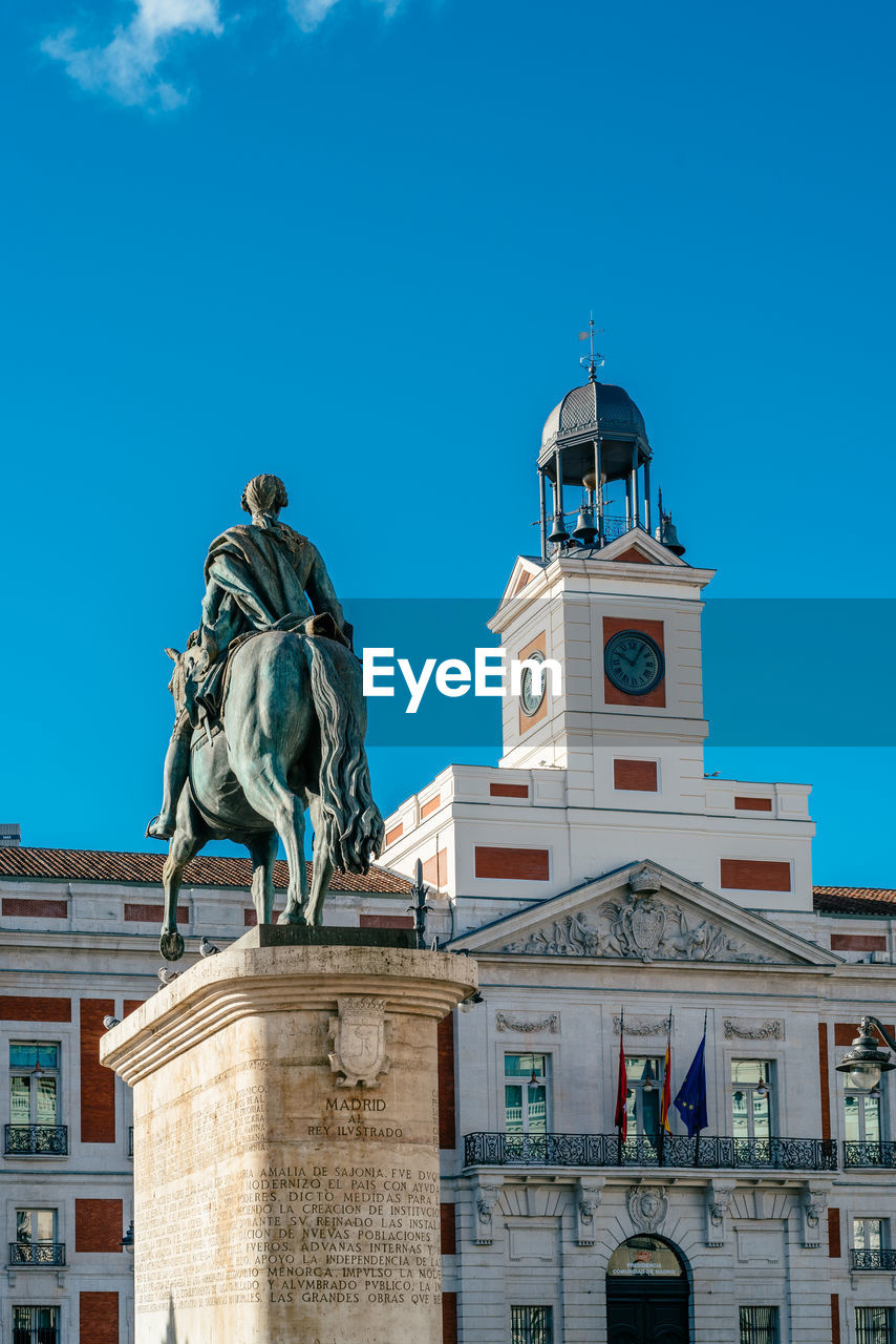 The puerta del sol square in central madrid. king charles iii statue and clock tower