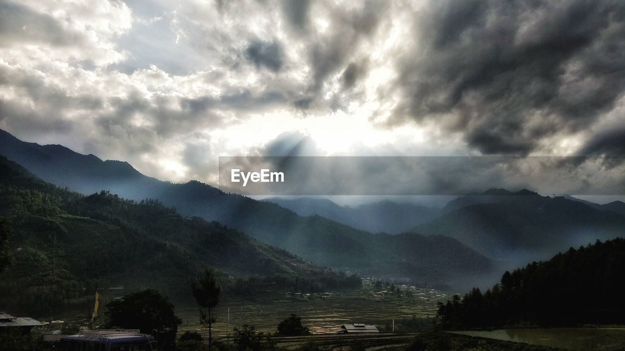 SCENIC VIEW OF MOUNTAIN RANGE AGAINST STORM CLOUDS