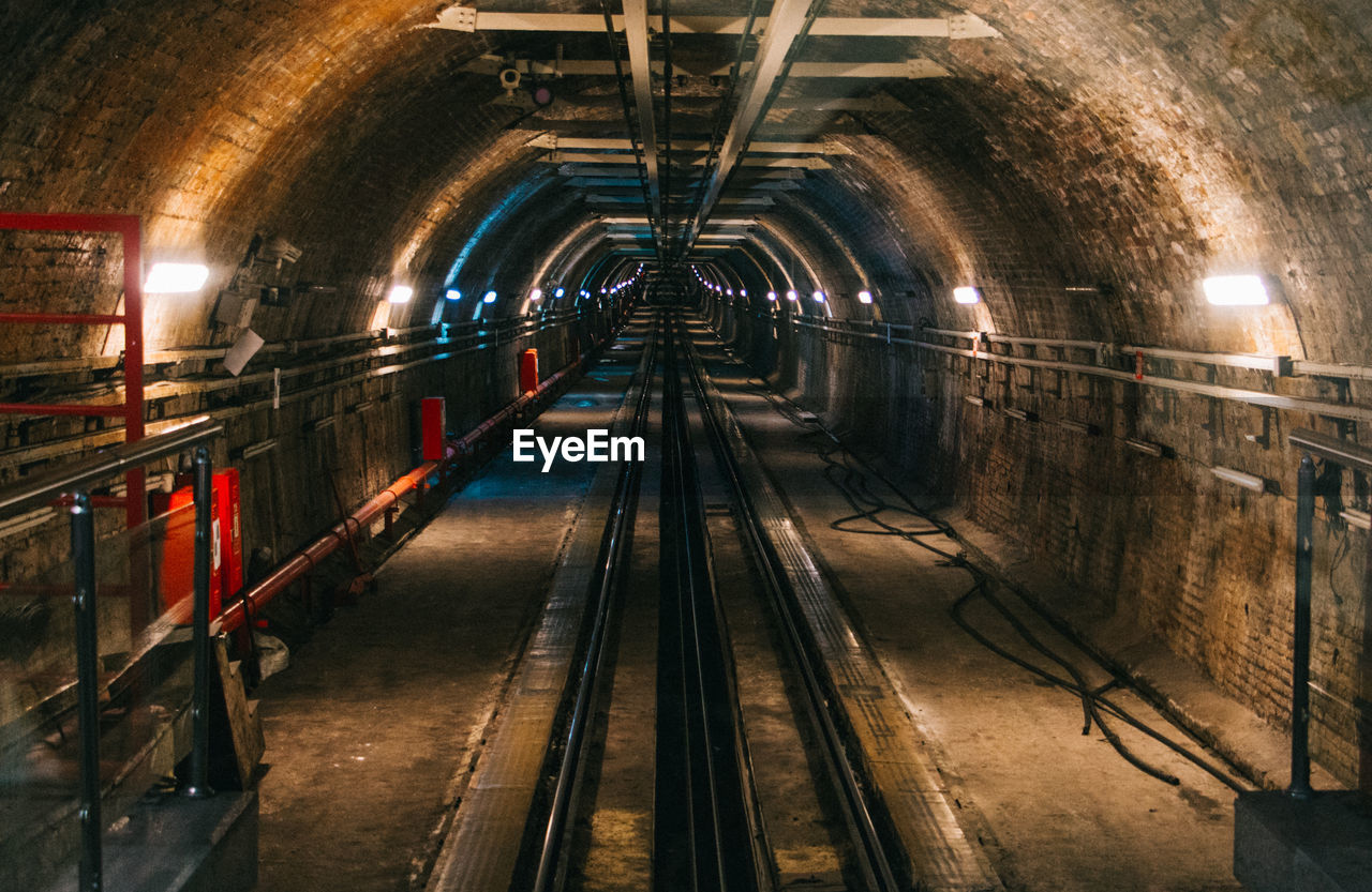 Railroad tracks in illuminated tunnel