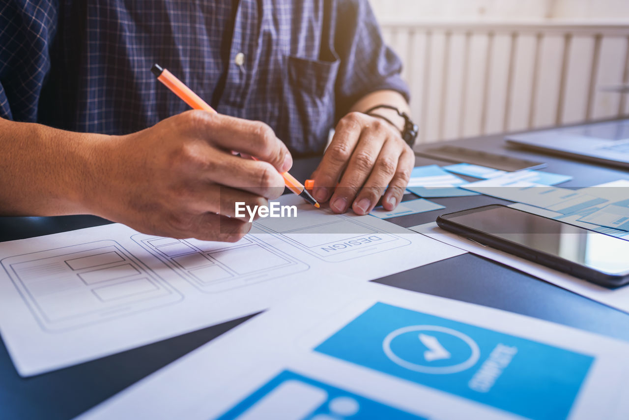 Midsection of businessman writing on table in office