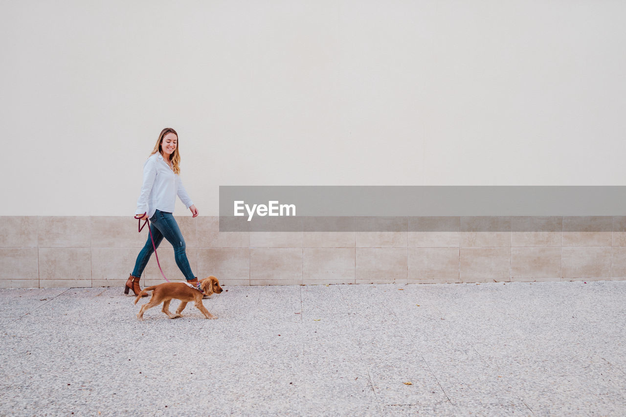 Full length of woman with dog walking on footpath