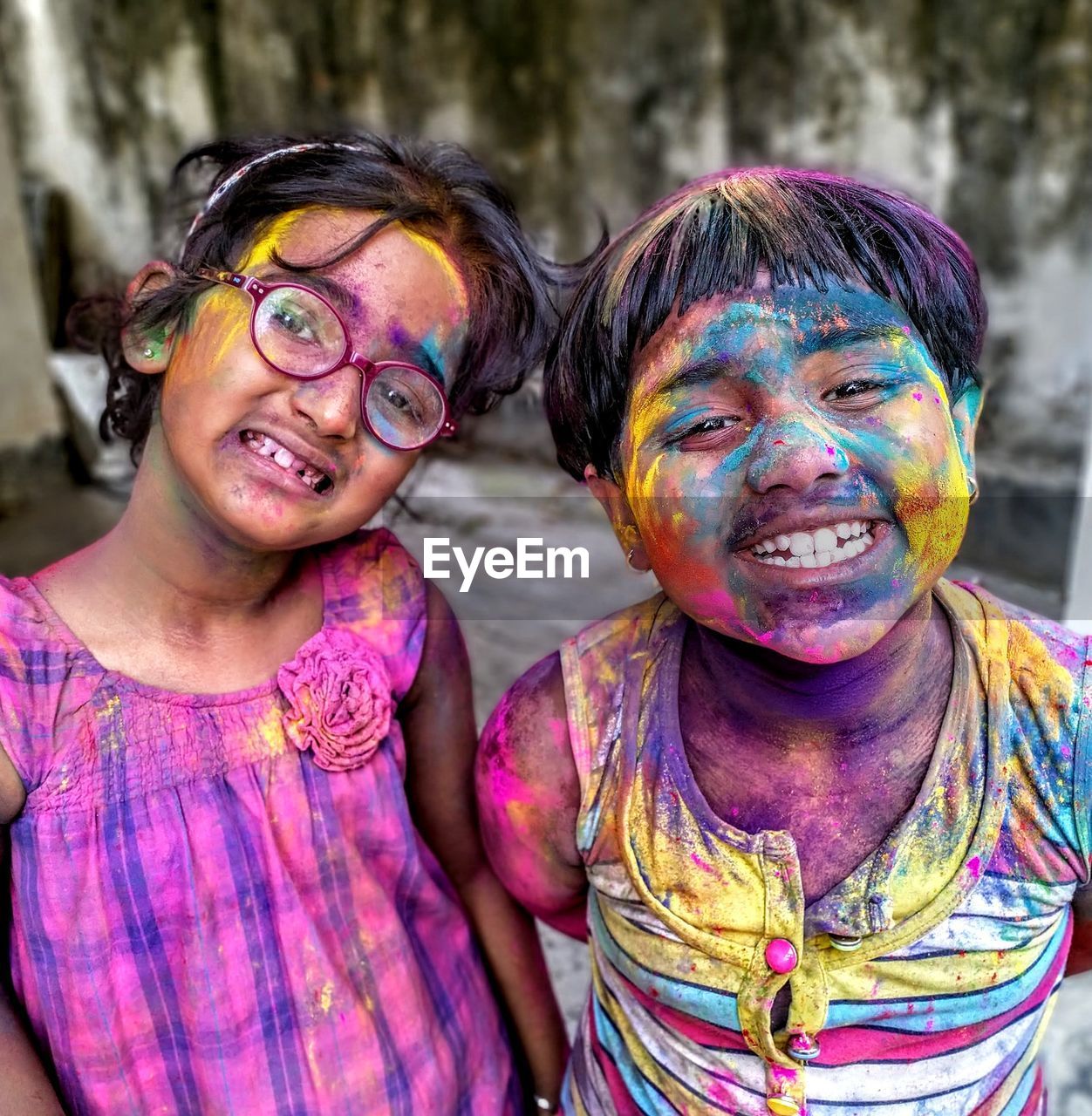 Portrait of smiling sisters with powder paint on face during holi