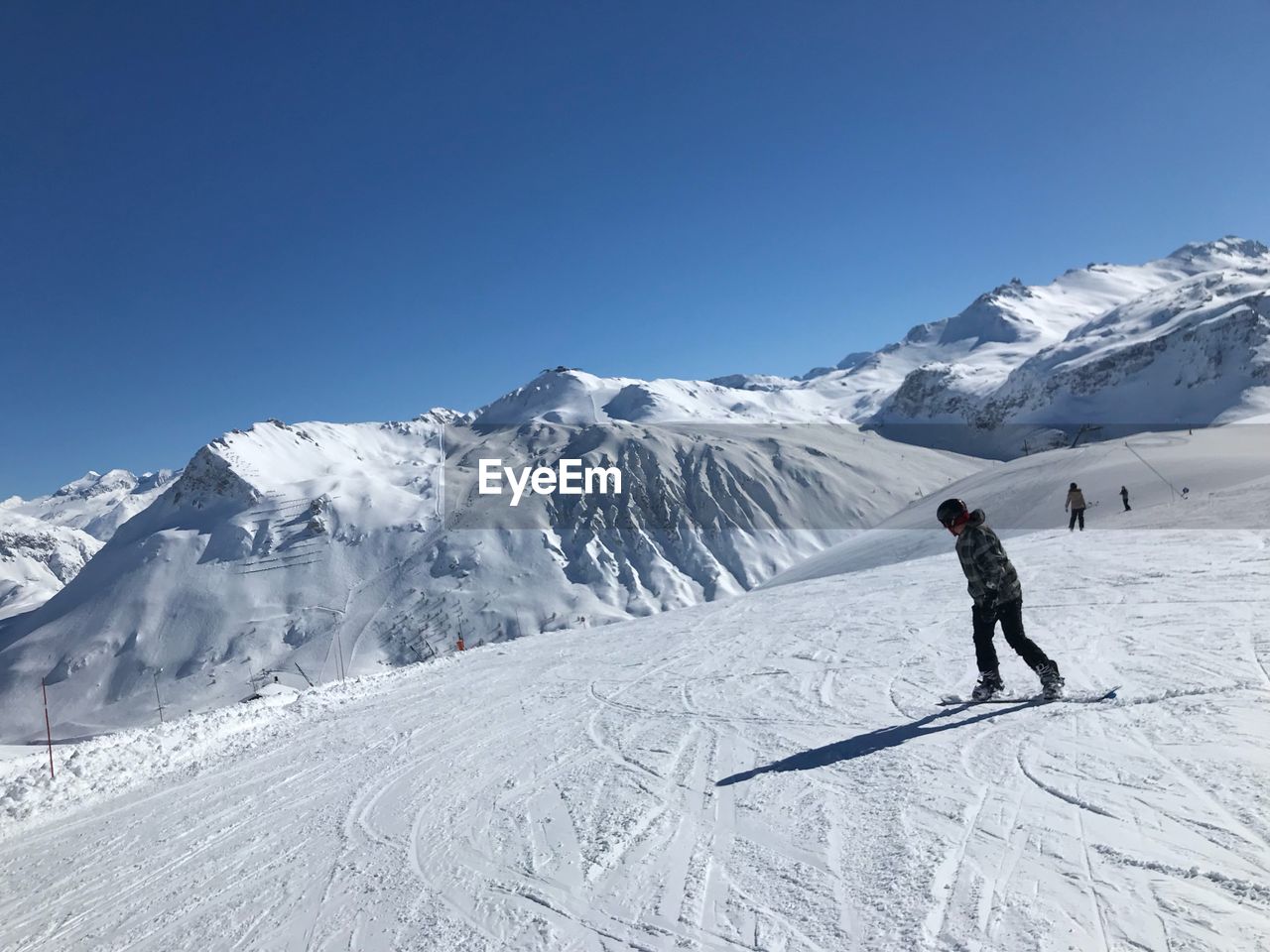 Woman snowboarding on snowcapped mountain against clear sky