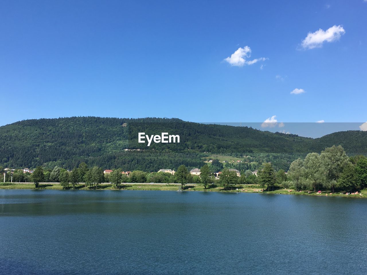 Scenic view of lake and mountains against blue sky