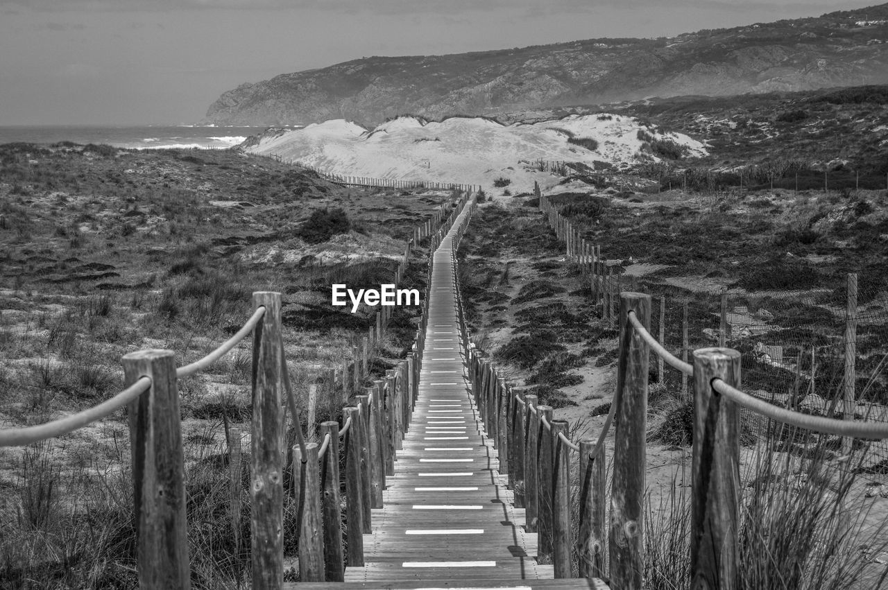 Narrow long footbridge on rocky shore