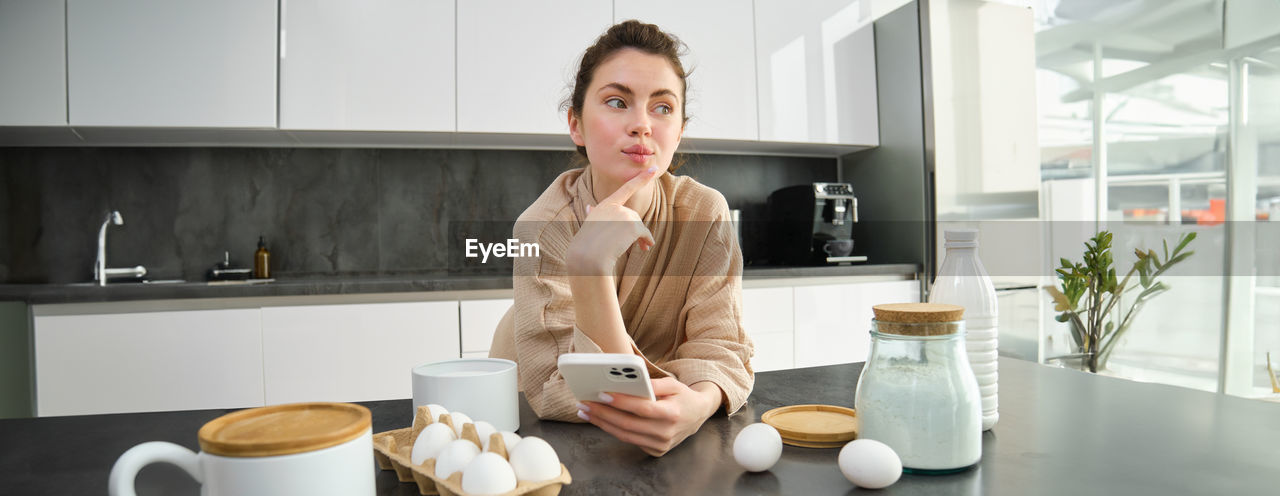 portrait of young woman using mobile phone on table