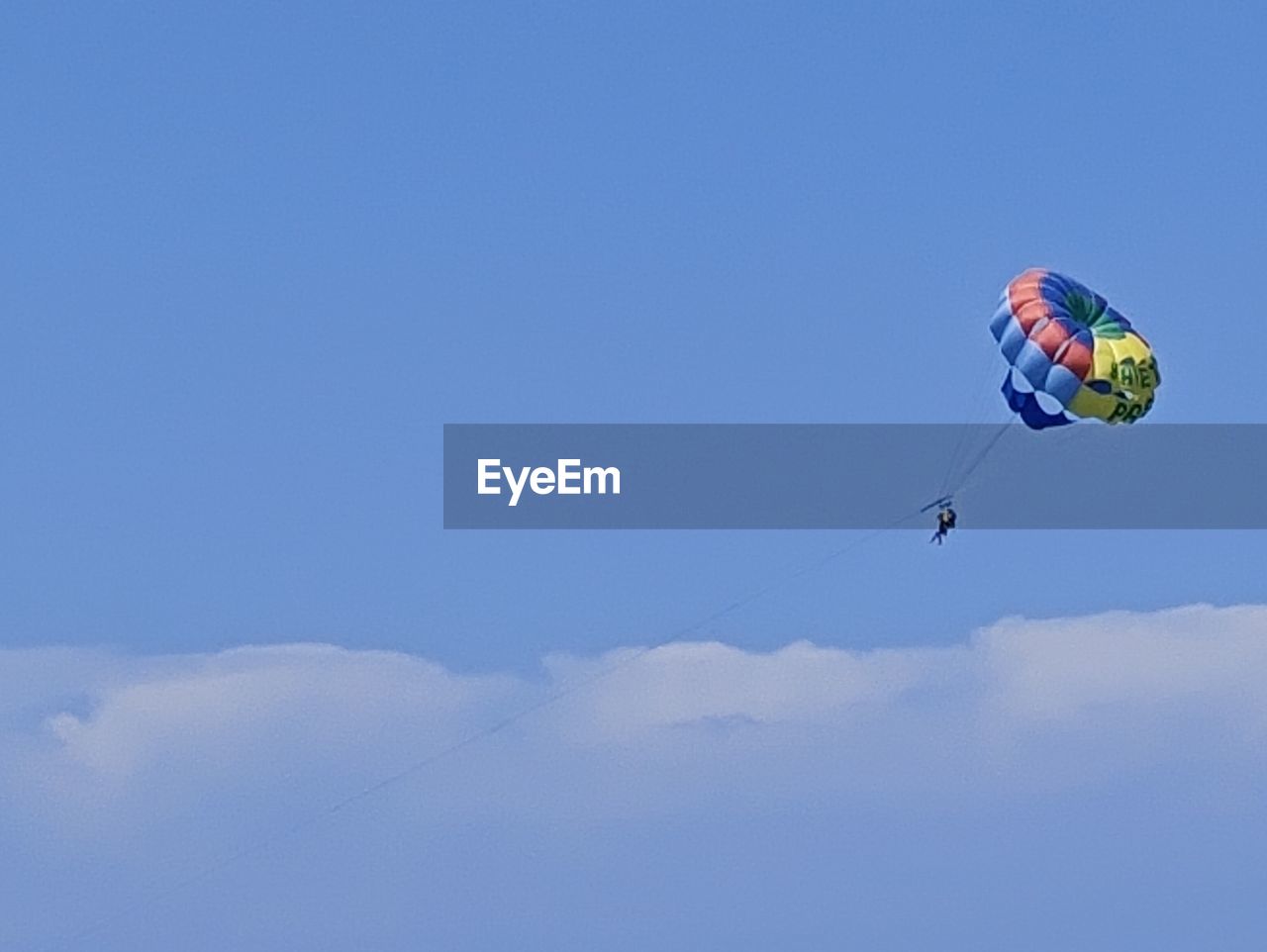 sky, adventure, flying, extreme sports, sports, mid-air, paragliding, parachute, blue, leisure activity, nature, windsports, joy, low angle view, transportation, cloud, day, exhilaration, motion, environment, vacation, parachuting, parasailing, recreation, trip, one person, holiday, gliding, fun, toy, multi colored, outdoors, copy space, kite sports, clear sky, air vehicle, lifestyles, individual sports, enjoyment, water sports, wind