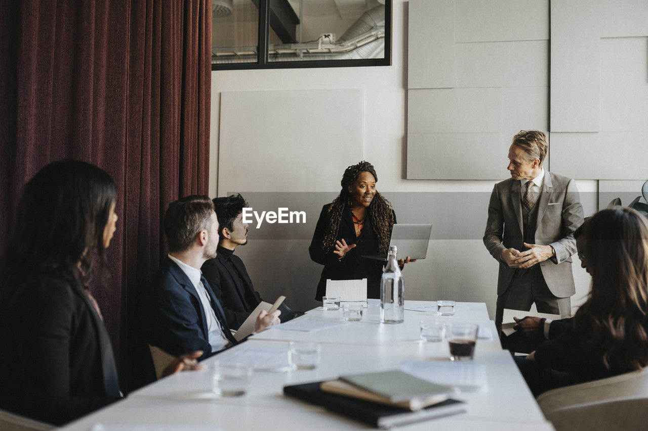 Female entrepreneur discussing with male and female coworkers during business meeting at office