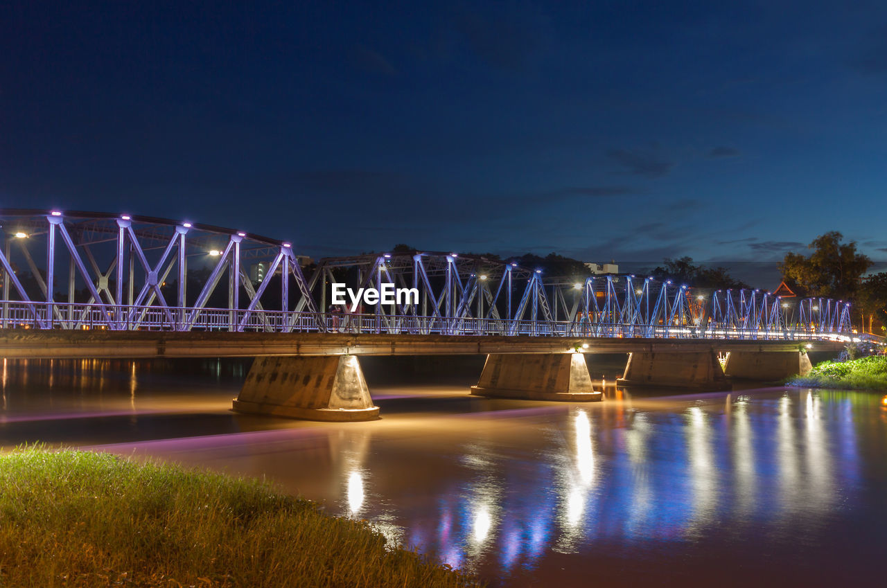 ILLUMINATED BRIDGE OVER RIVER AGAINST SKY