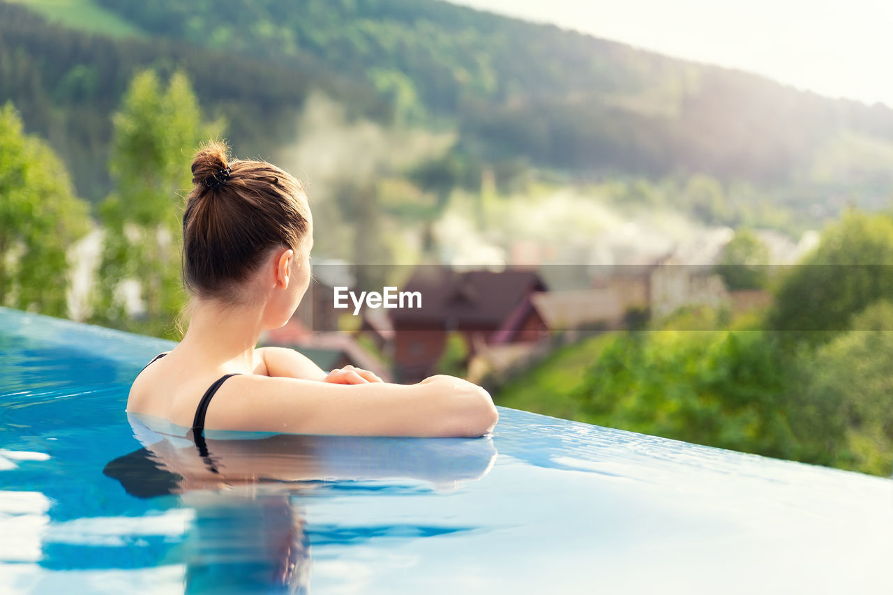 REAR VIEW OF WOMAN ON SWIMMING POOL