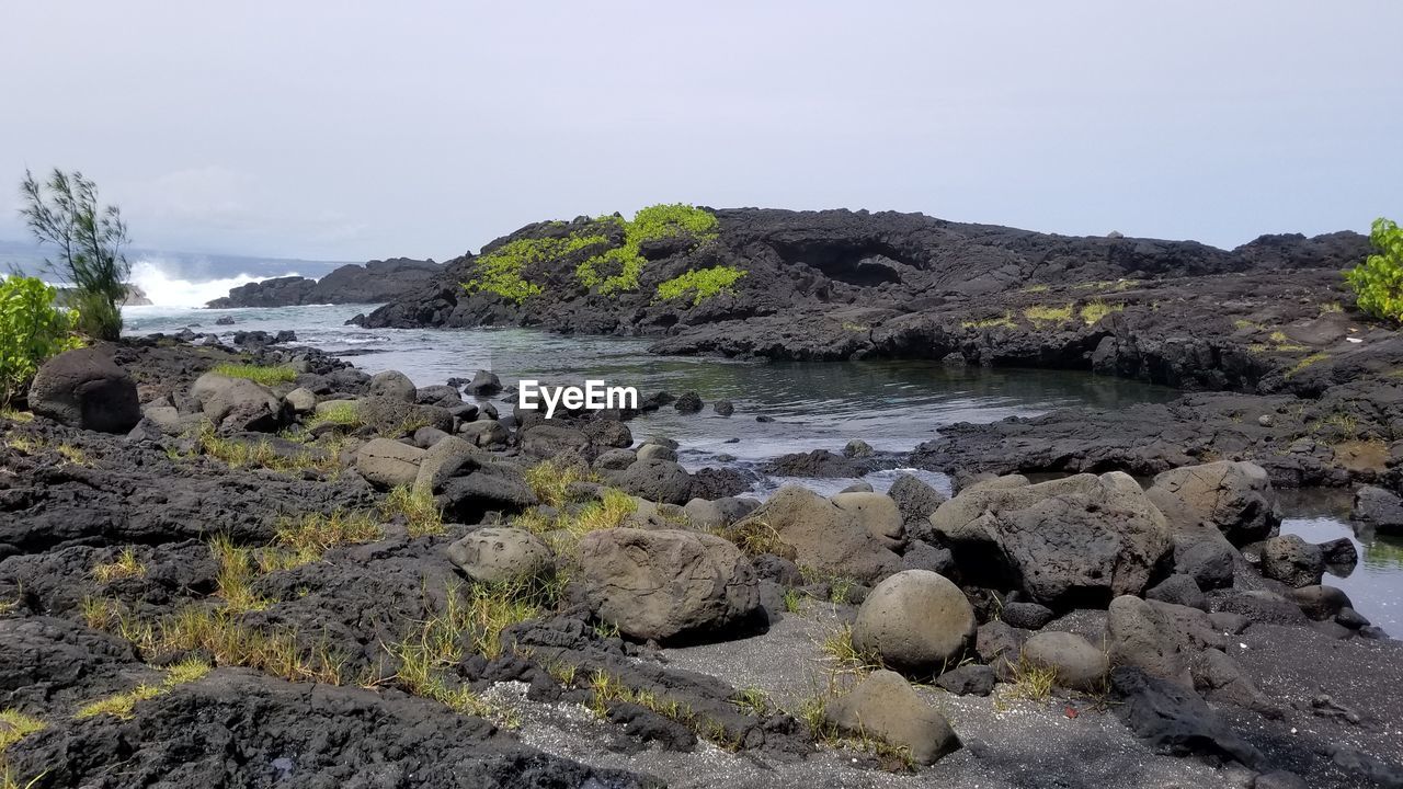 ROCKS ON SHORE AGAINST CLEAR SKY