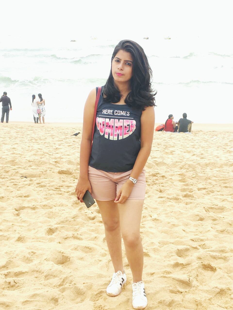 FULL LENGTH PORTRAIT OF HAPPY YOUNG WOMAN ON SANDY BEACH