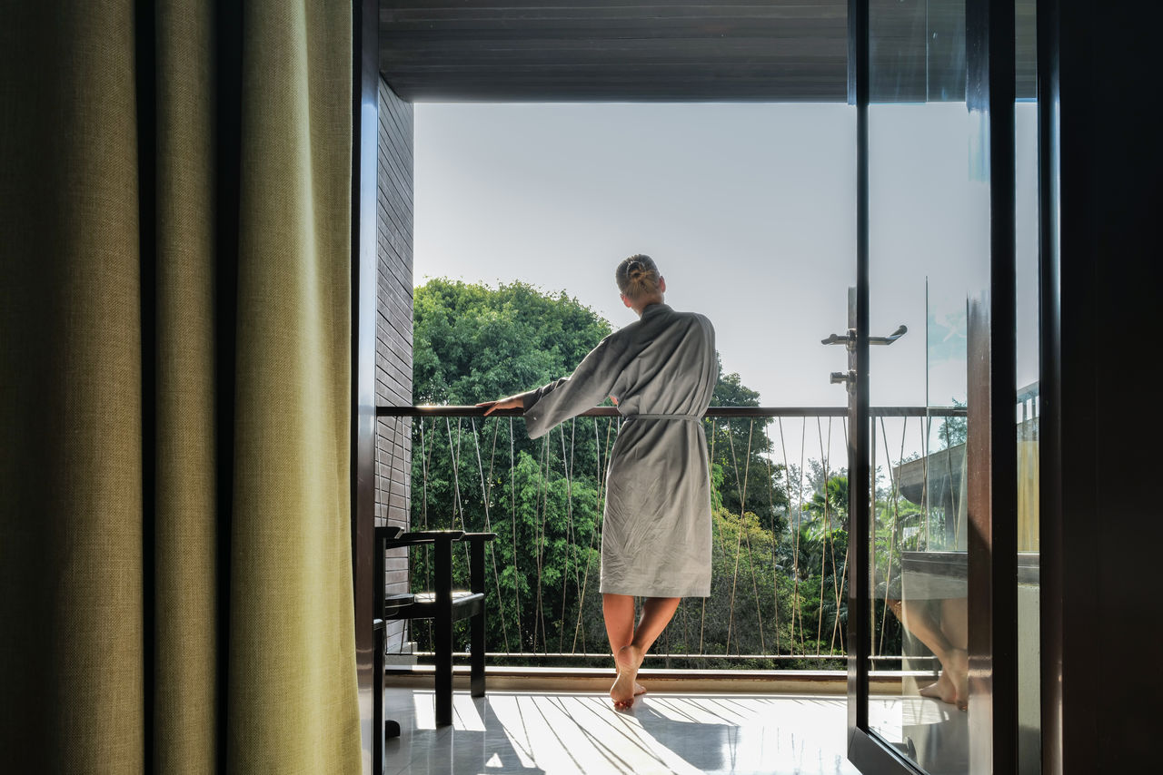 Side view of young man looking through window