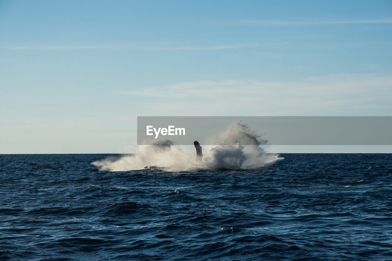 SEA WAVES SPLASHING AGAINST BLUE SKY