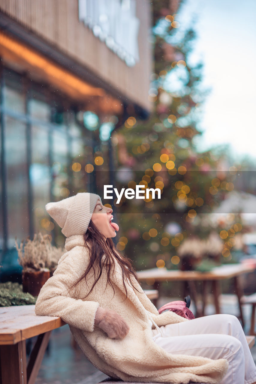 Woman looking away while standing by tree