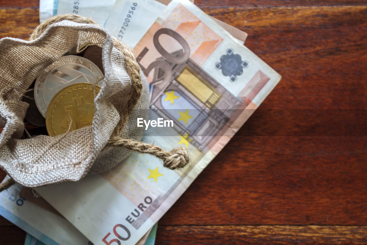 High angle view of coins and paper currency on table