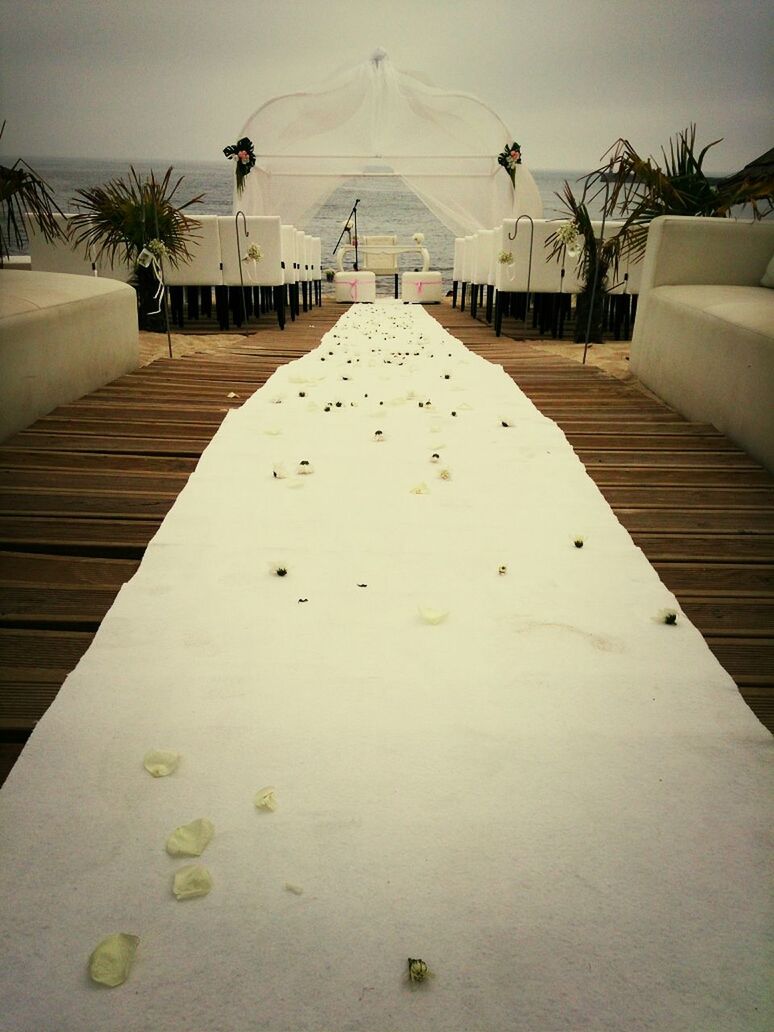 Narrow pathway leading to chairs on beach