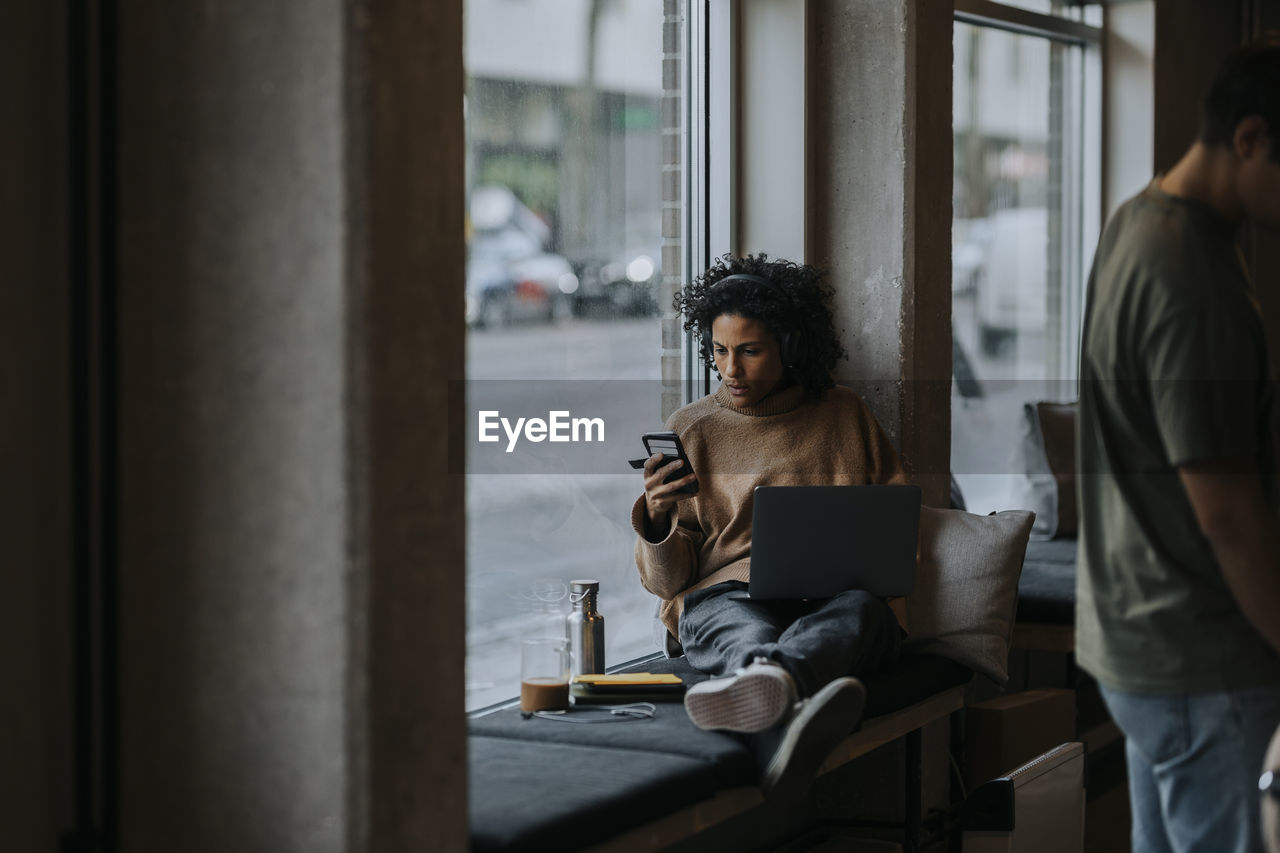 Businesswoman using smart phone while working by male colleague in startup company