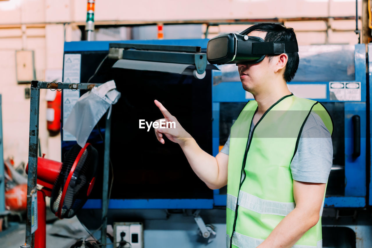 Man gesturing while wearing virtual reality simulator in factory