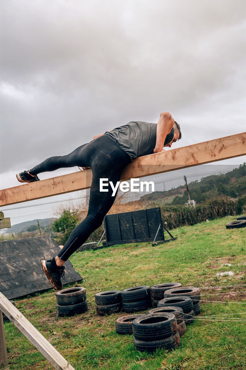 Man jumping on wood against sky