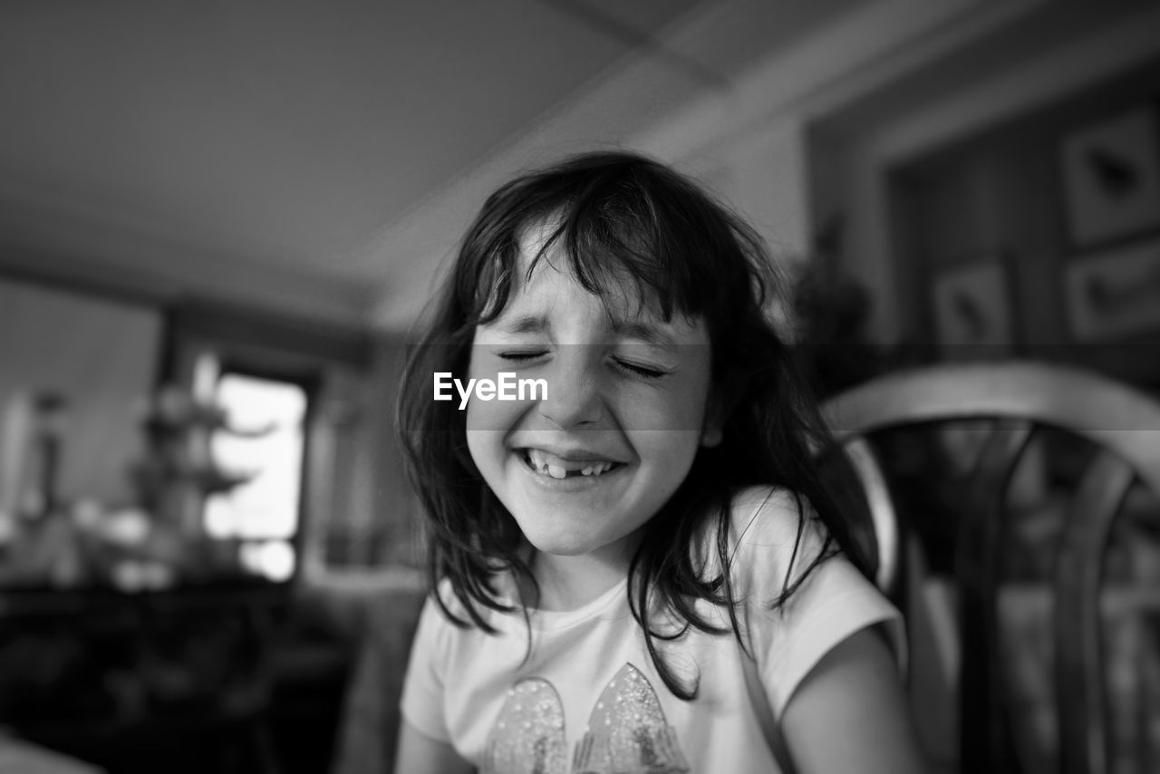 Close-up of girl smiling while sitting at home