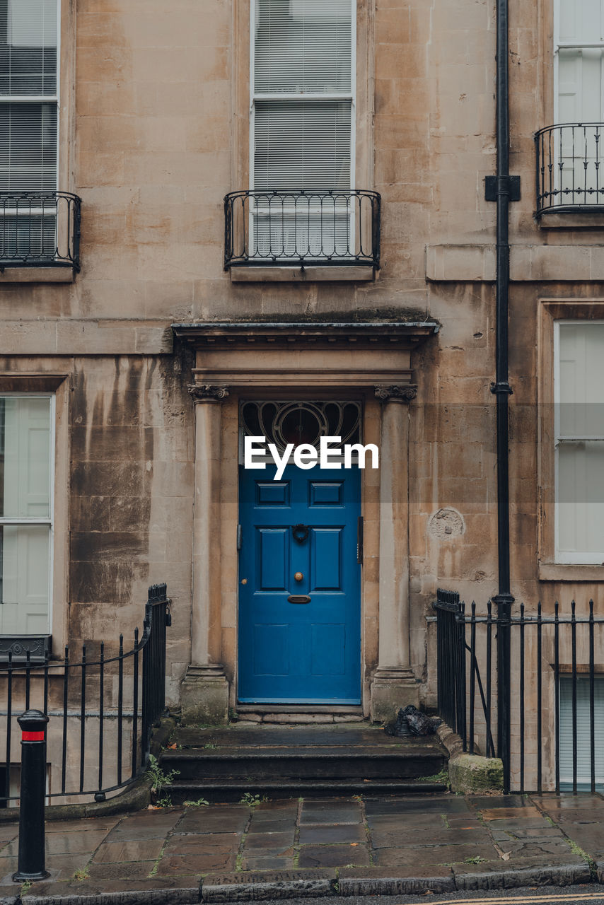 Bright blue front door on a traditional limestone terraced house in bath, somerset, uk.