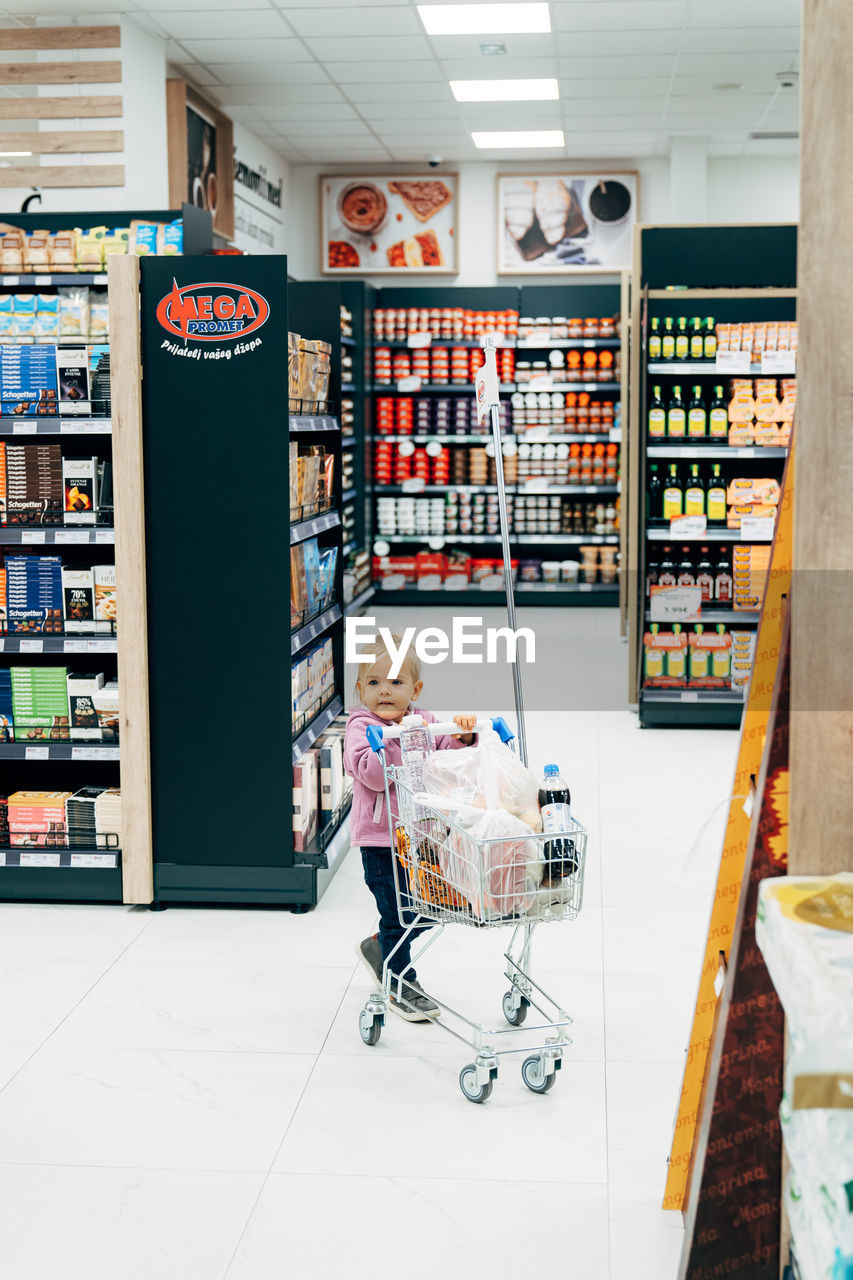 FULL LENGTH OF WOMAN STANDING IN STORE AT SHOP