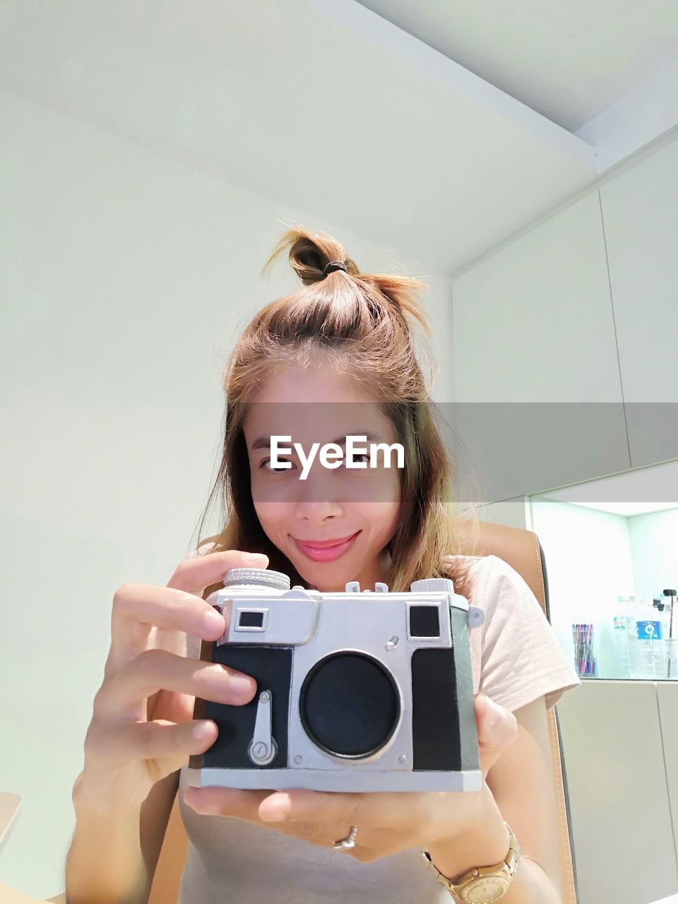 Portrait of smiling mid adult woman holding camera at home