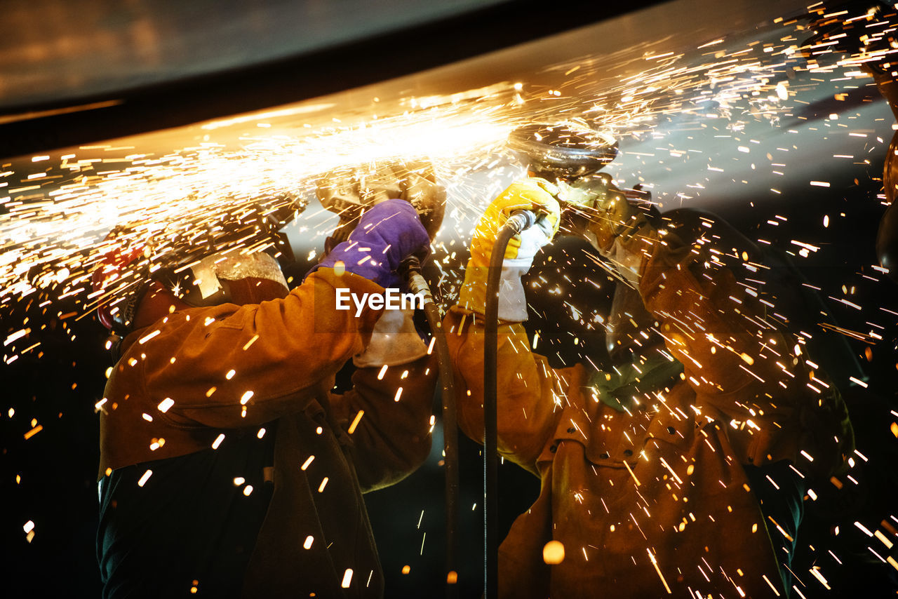 Mechanics welding airplane wing at industry during night