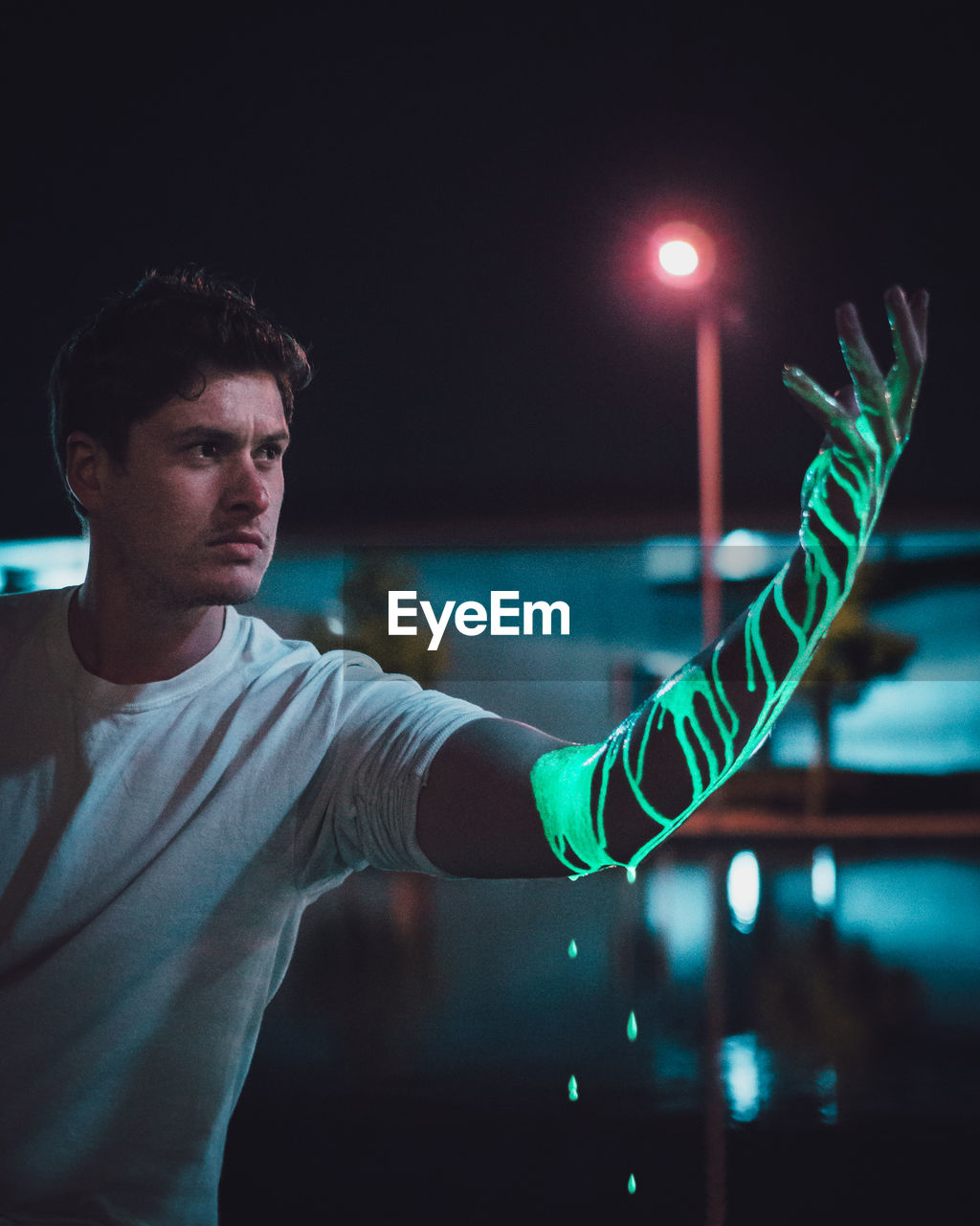 YOUNG MAN STANDING IN ILLUMINATED LIGHT