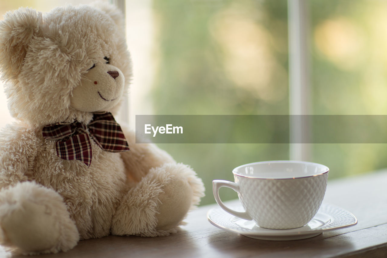 Close-up of teddy bear and coffee cup on table