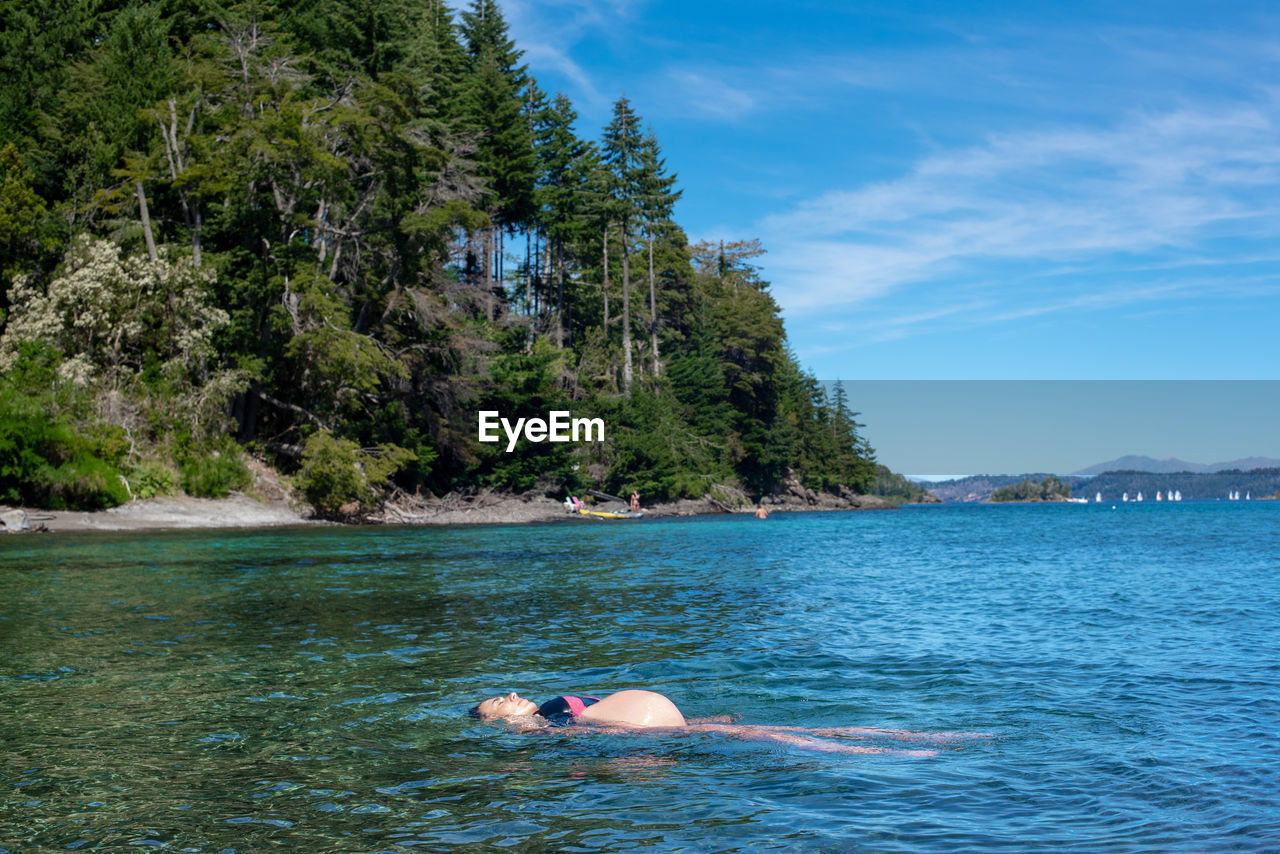 Man swimming in sea against sky