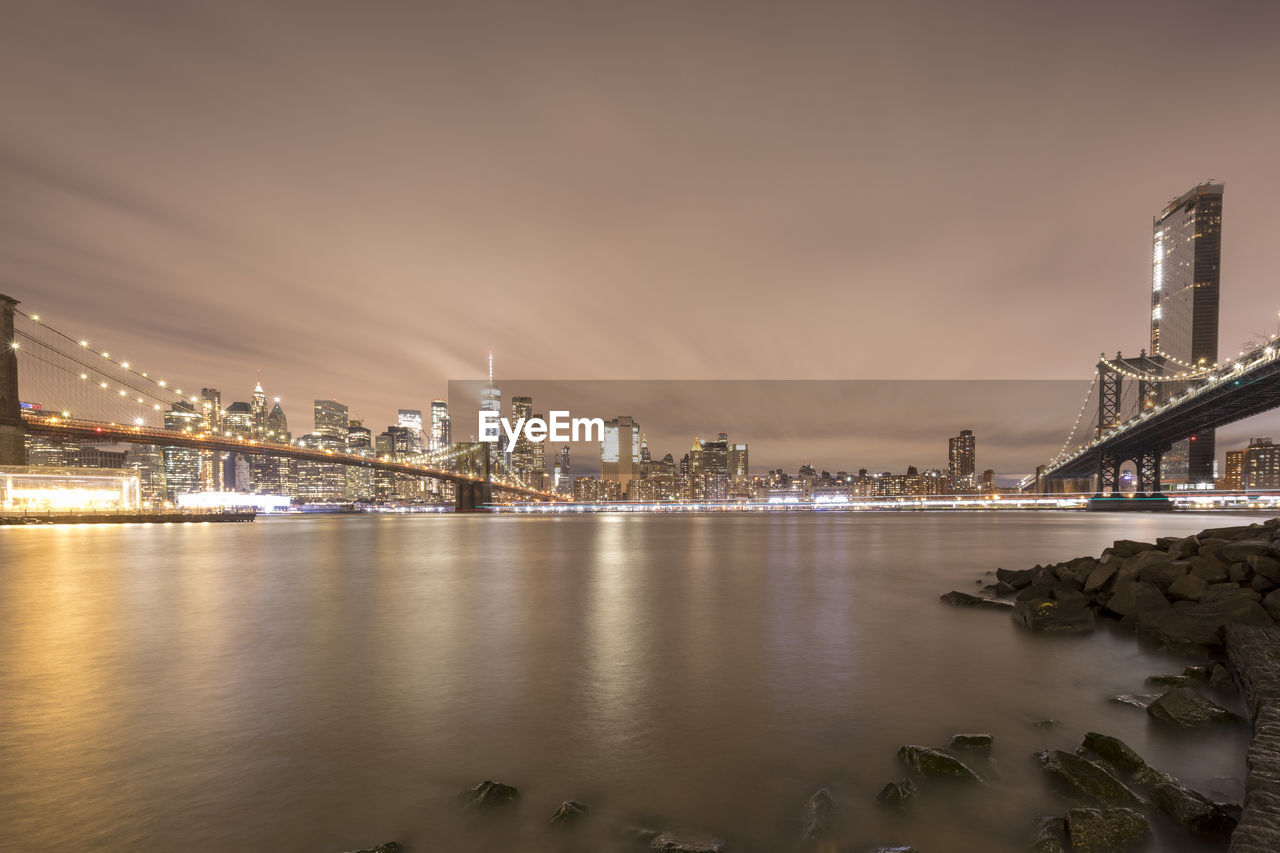 River by illuminated buildings against sky at night