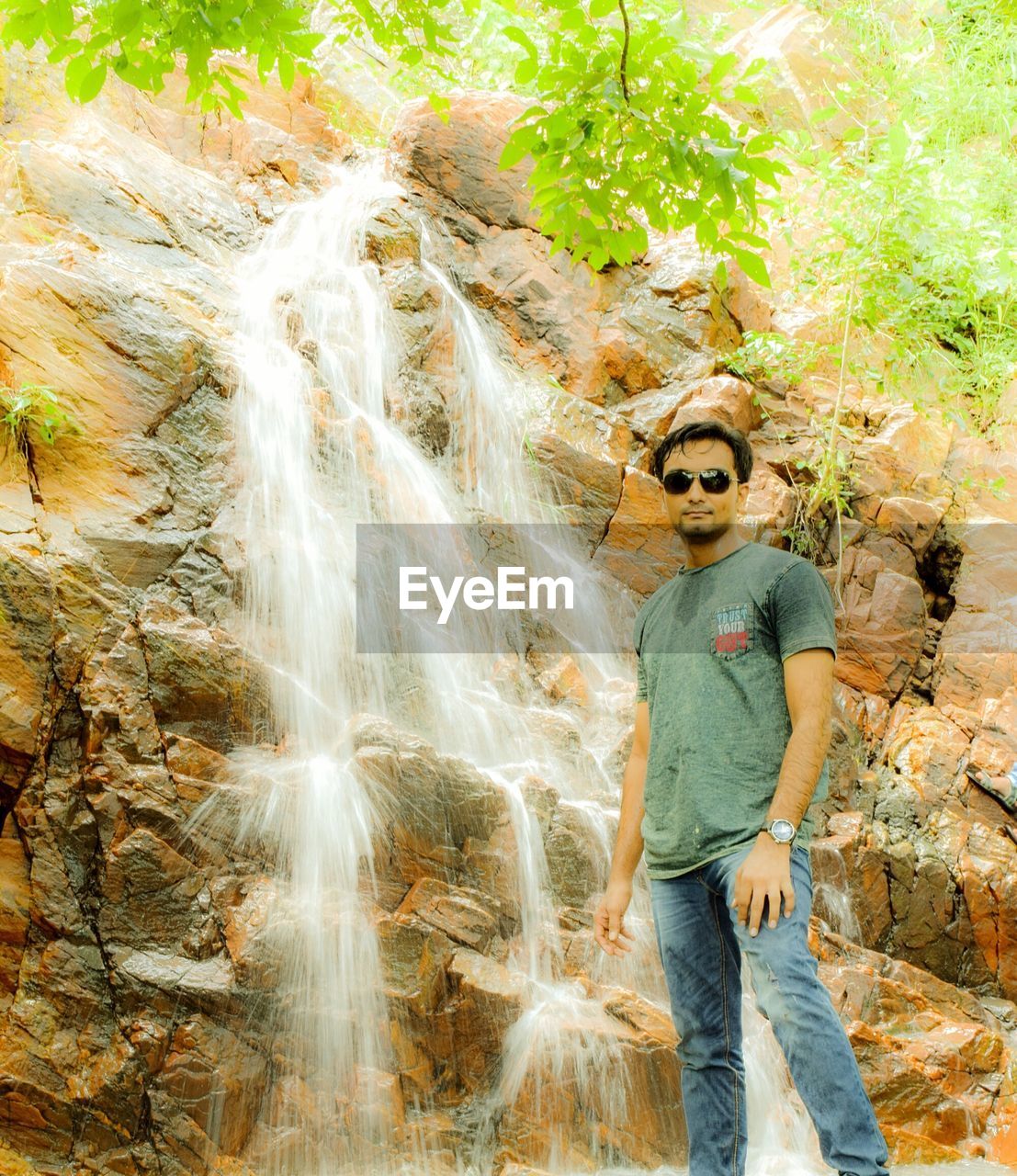 Man standing by waterfall