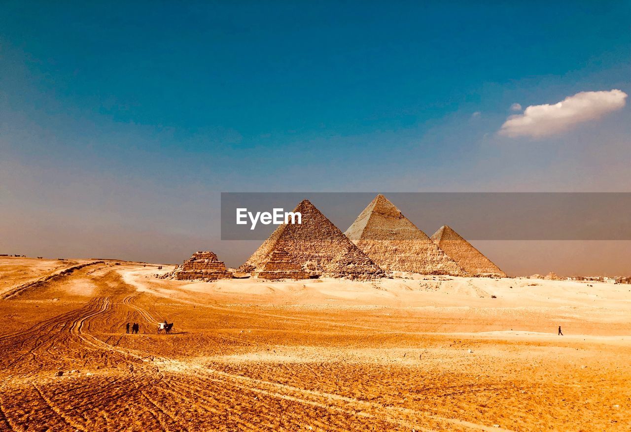 Pyramids at desert against blue sky