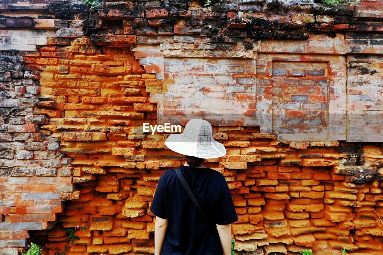 Woman standing in front of brick wall