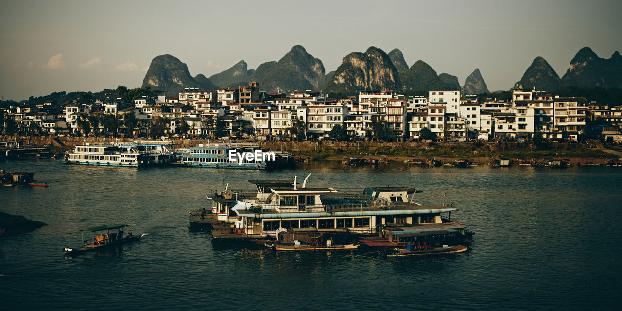 Boats on chinese river against sky and city