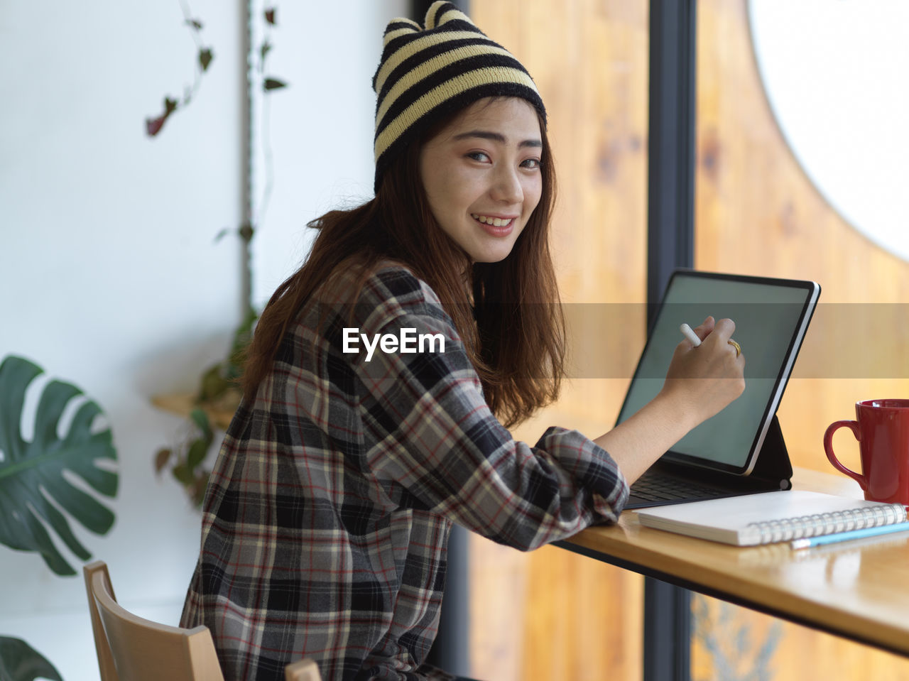 Young woman using digital tablet while sitting on table