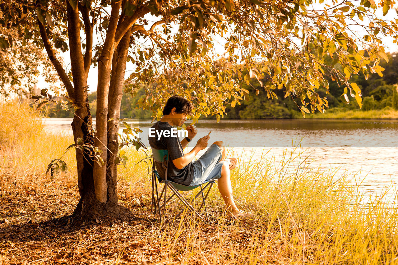 Man sitting by lake on chair