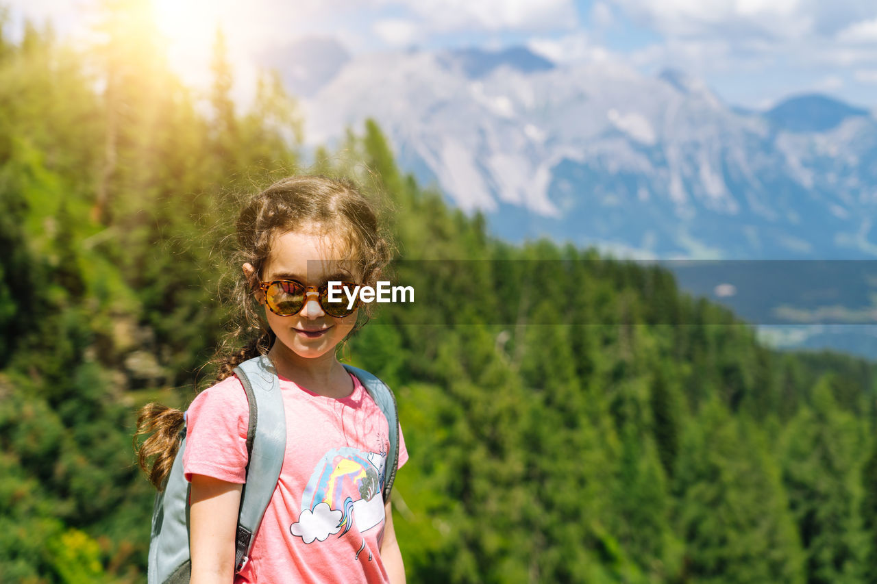 PORTRAIT OF SMILING GIRL AGAINST PLANTS