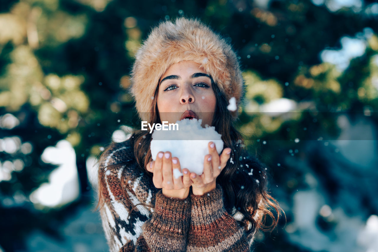 PORTRAIT OF YOUNG WOMAN WITH ICE CREAM IN SNOW