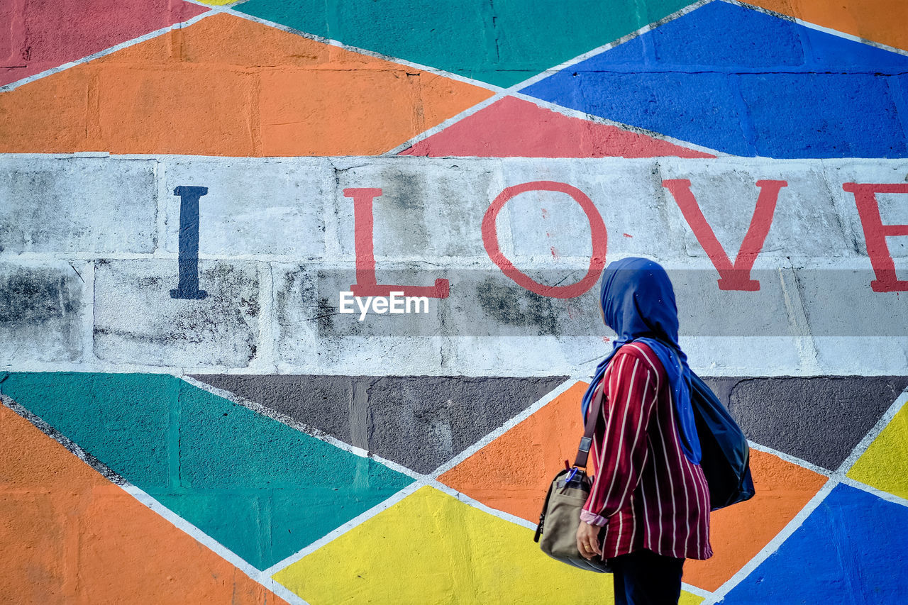 Woman standing by graffiti wall