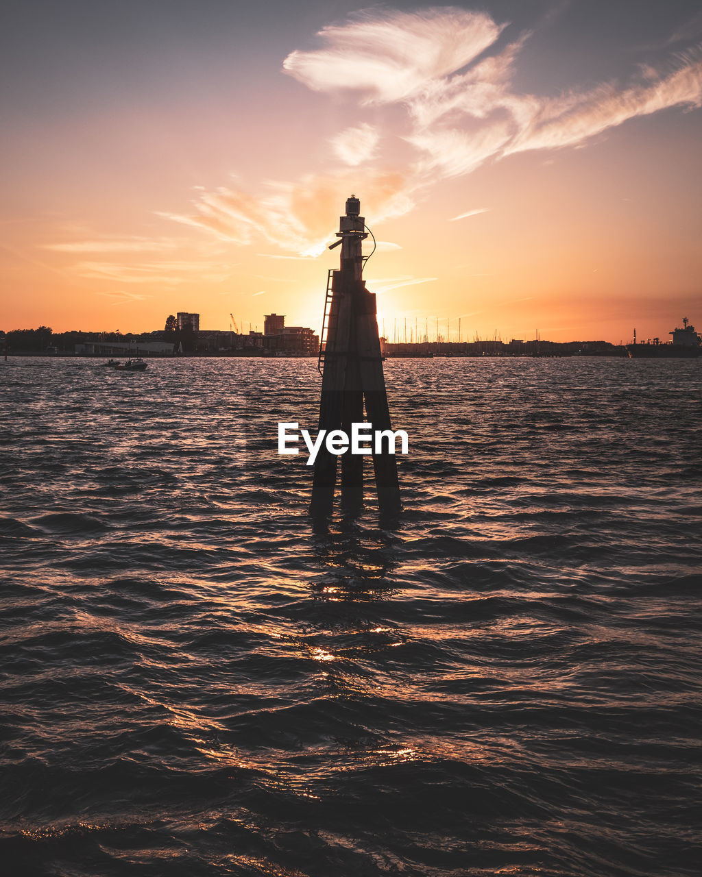 Silhouette structure in sea against sky during sunset