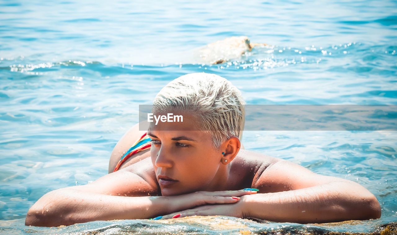 Portrait of shirtless woman swimming in sea on sunny day