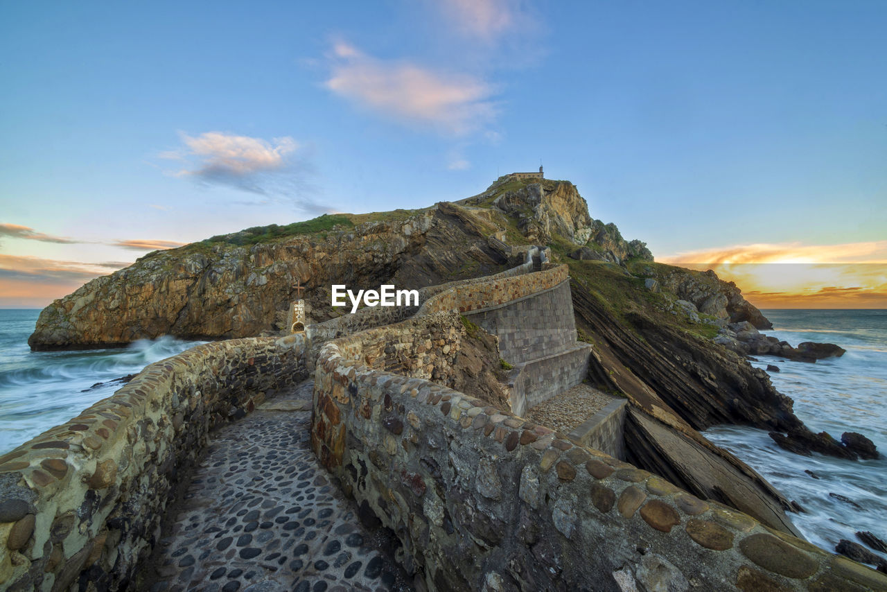 ROCK FORMATIONS ON SHORE AGAINST SKY