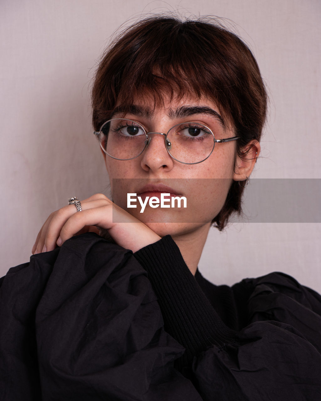 Portrait of young woman with eyeglasses against wall