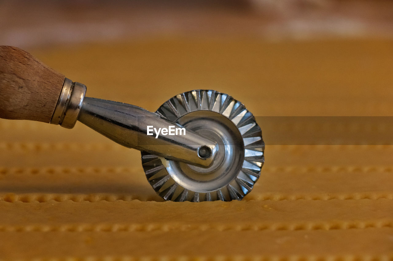 Detail of a steel pastry cutter wheel while cuts a layer of puff pastry