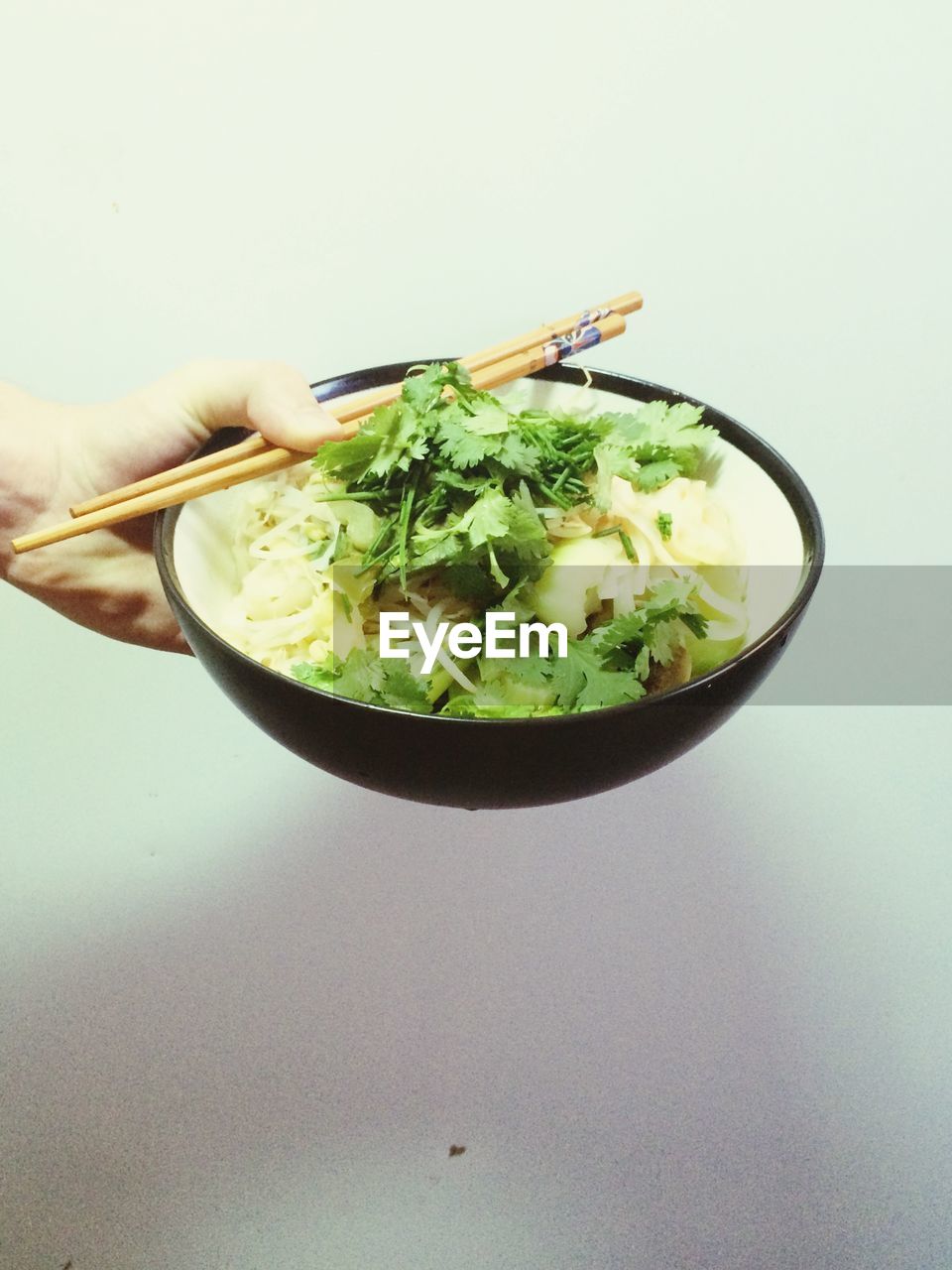 Cropped image of person holding noodles against white wall at home